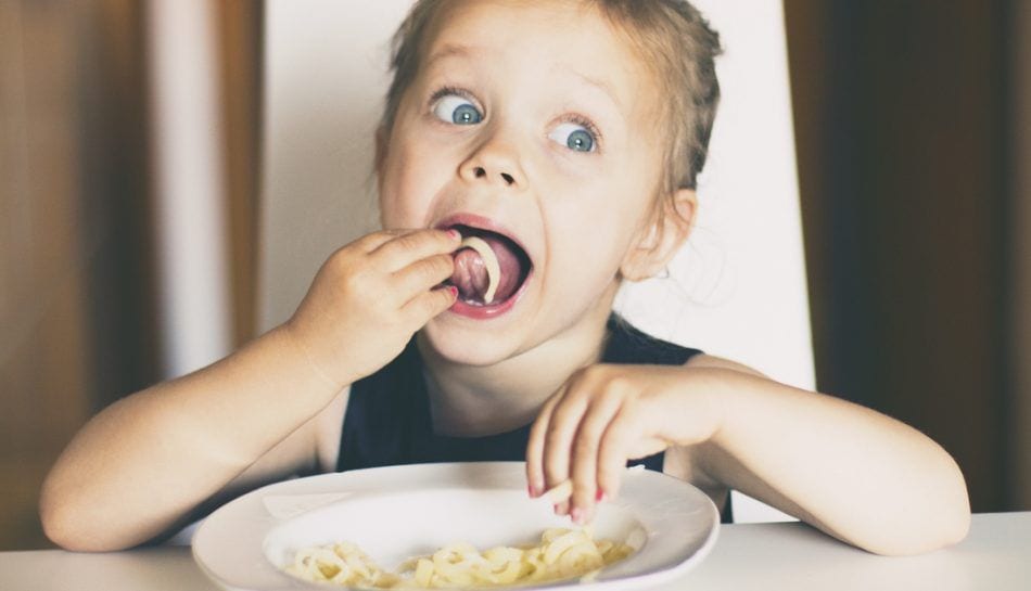 Un bambino che mangia, felice, la pasta